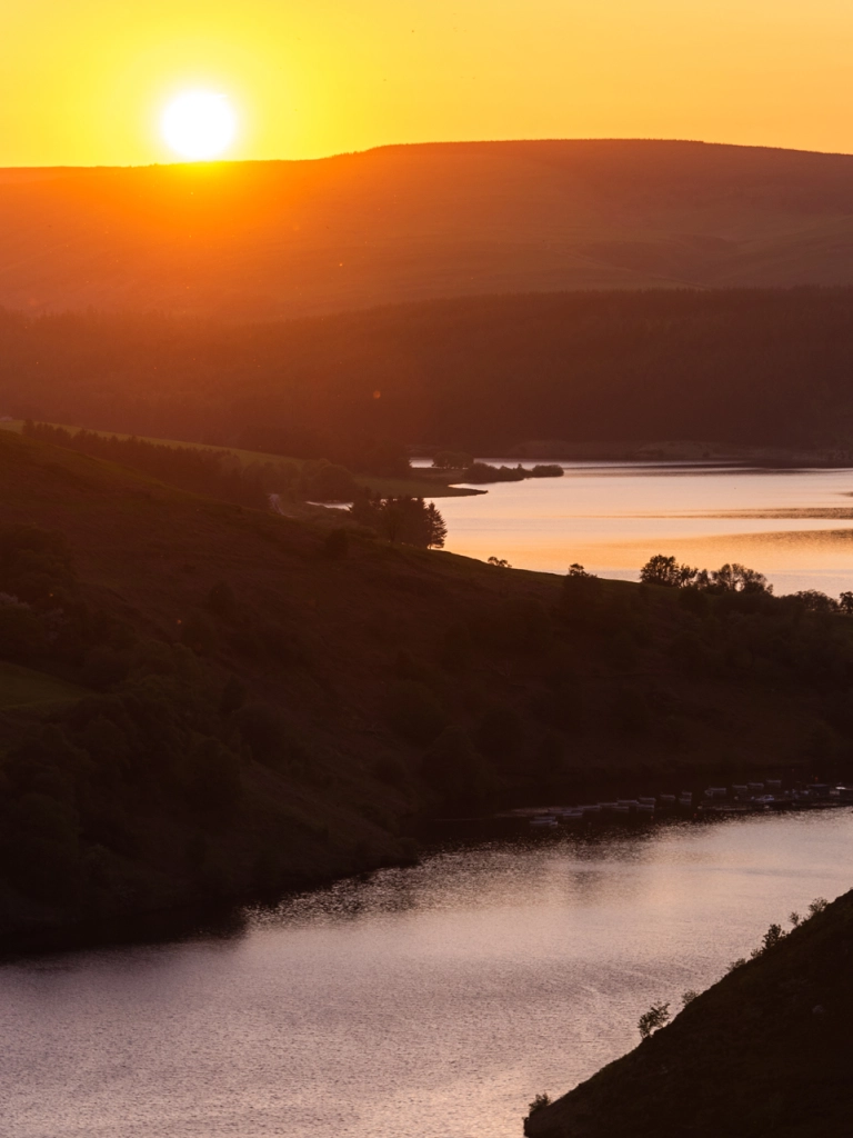 Sunset over mountains over a large lake.