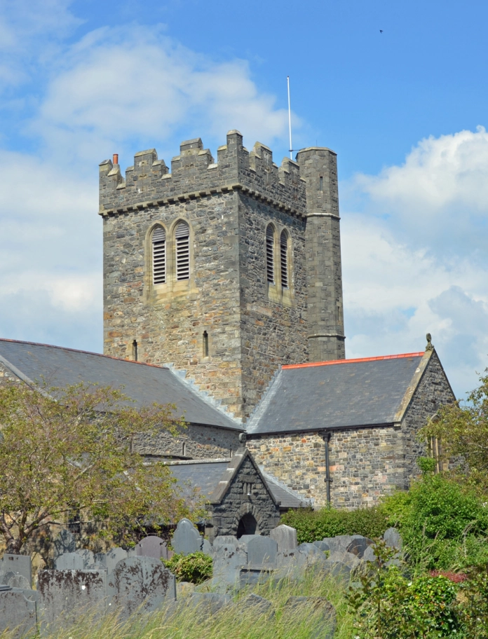 A grey stone church in a slate tombstoned graveyard.