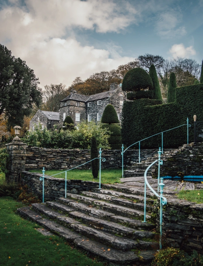 garden with steps, trees and house in background.