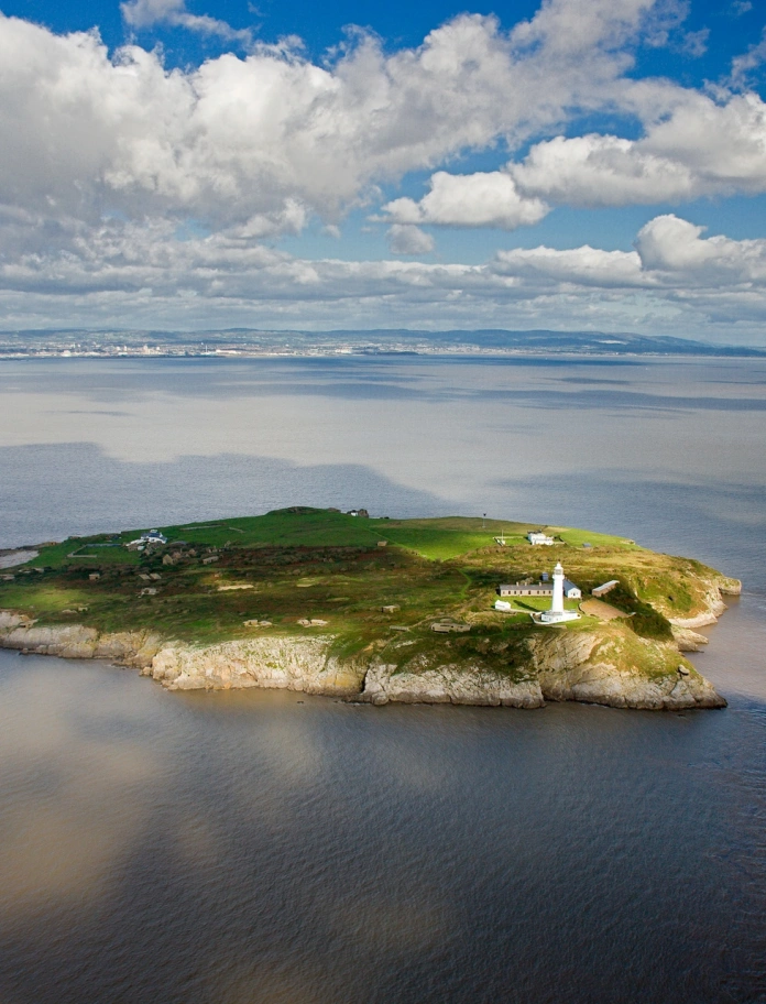 A lighthouse on a headland surrounded by the sea.