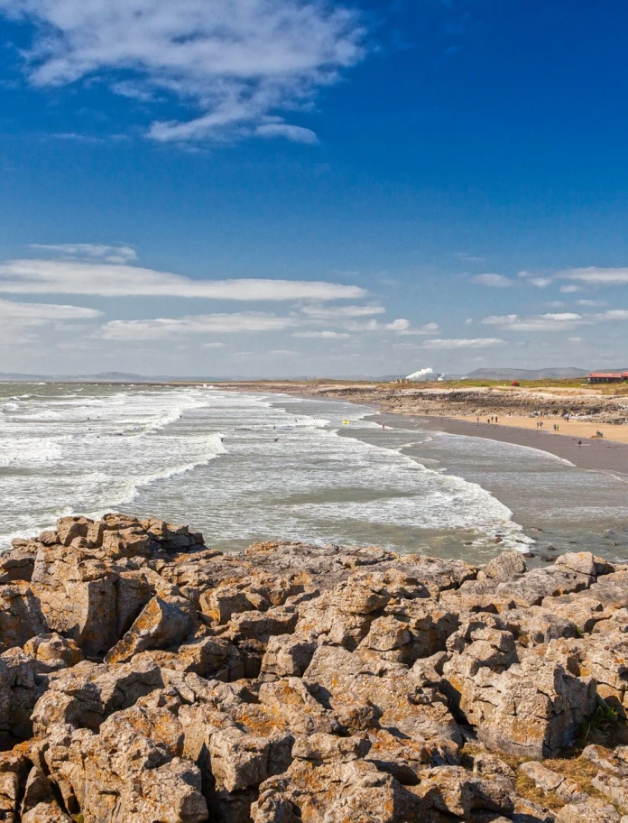 sandy beach with tide coming in, viewed from rocks.