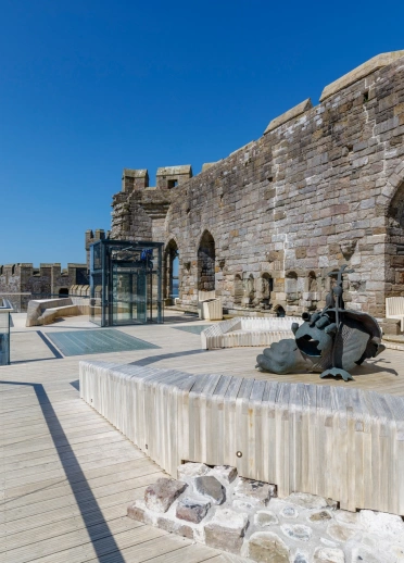 A wide walkway on stone castle walls with a lift.