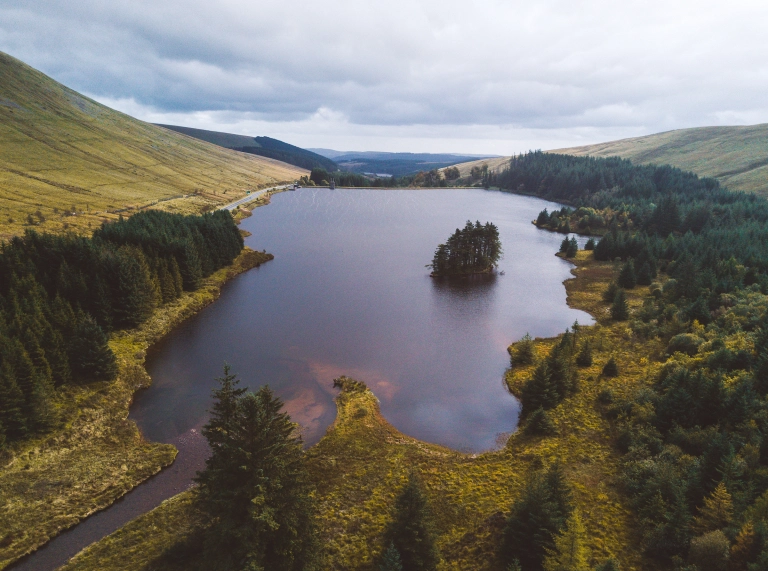 Aerial image for the Beacons Reservoir with trees and hills surrounding the reservoir, and a small wooded island in the middle of the water