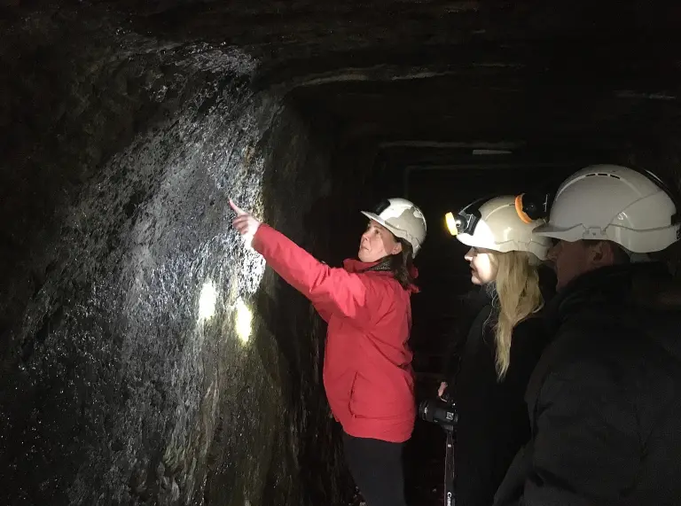 People with hard hats on inside a mine.