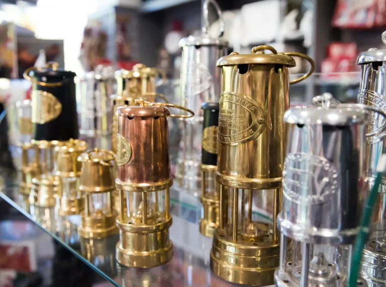Rows of colourful shiny miners lanterns on display in a cafe.