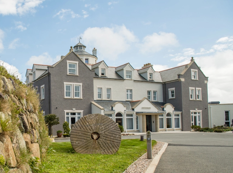 A grey and white painted hotel with a windmill tower.