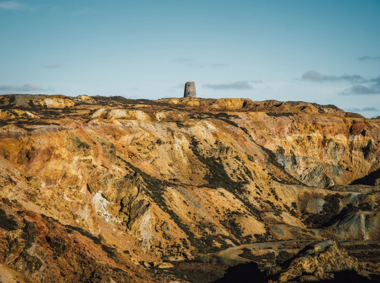 A quarry with colourful layers of ground, mainly yellow.