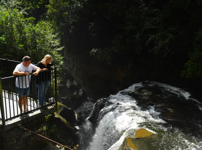 Two people on an outdoor balcony overlooking a waterfall.