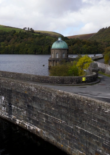photo of the river held back by the dam with a forest and mountains in the background