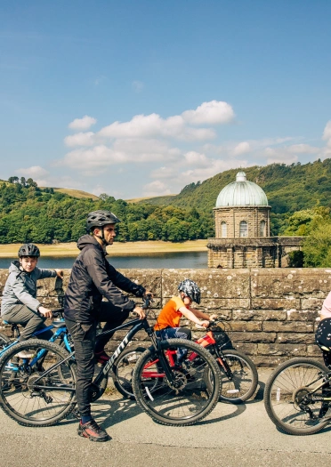family cycling with reservoir in background.