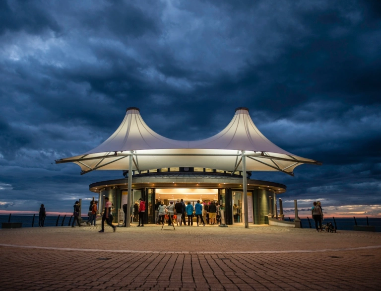 Food pavilion with people gathered around silhouetted against a dusk sky