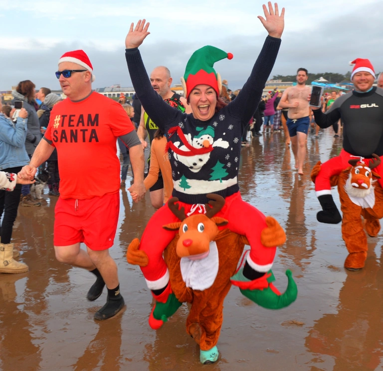 people in festive fancy dress on the beach.