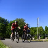 Two people cycling alongside the river
