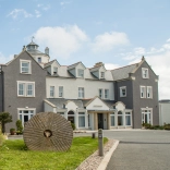 A grey and white painted hotel with a windmill tower.