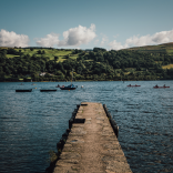 Lake with pontoon in foreground and boats and countryside in background.