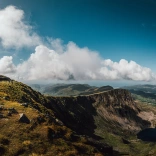 View from a mountaintop including the summit and towards the coast.