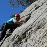 man with safety equipment climbing cliff on sunny day.